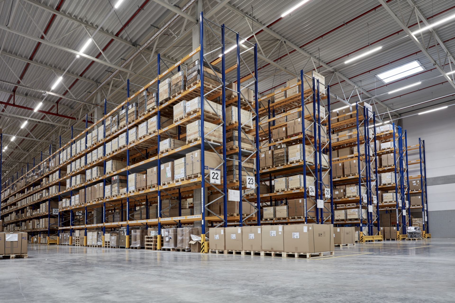 A warehouse with several boxes stacked on pallets in shelves