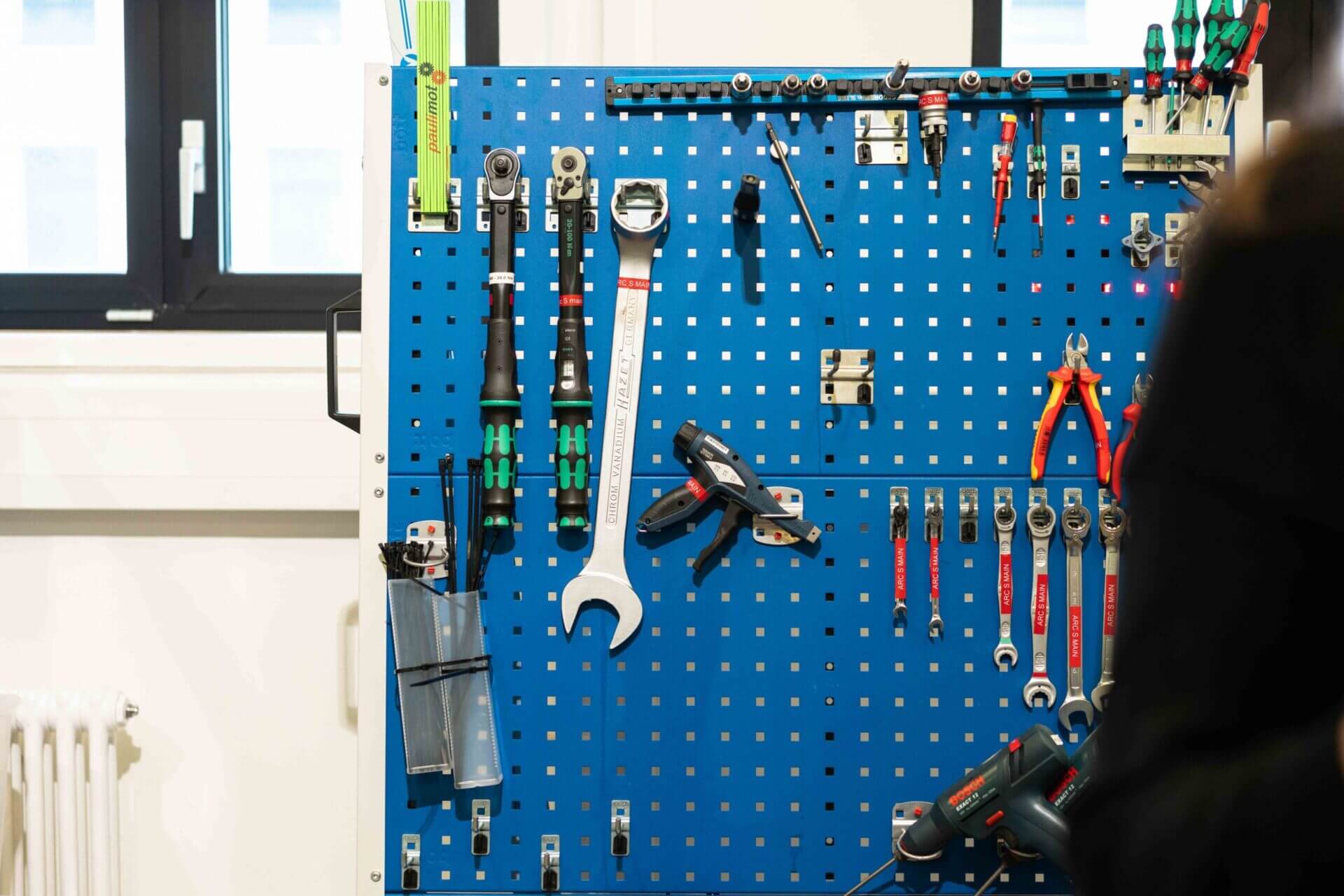 An image of different AMR production tools such as wrenches, pliers, and screwdrivers hanging on a tool board. 