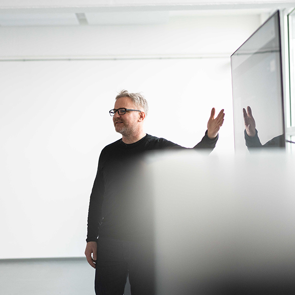 A photo of our product owner for the arculus fleet manager during a presentation. He is standing sideways while pointing at a tv.