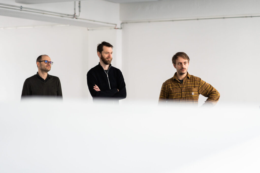 3 members of the commercial team at arculus standing in a bright workspace, highlighting collaboration and teamwork